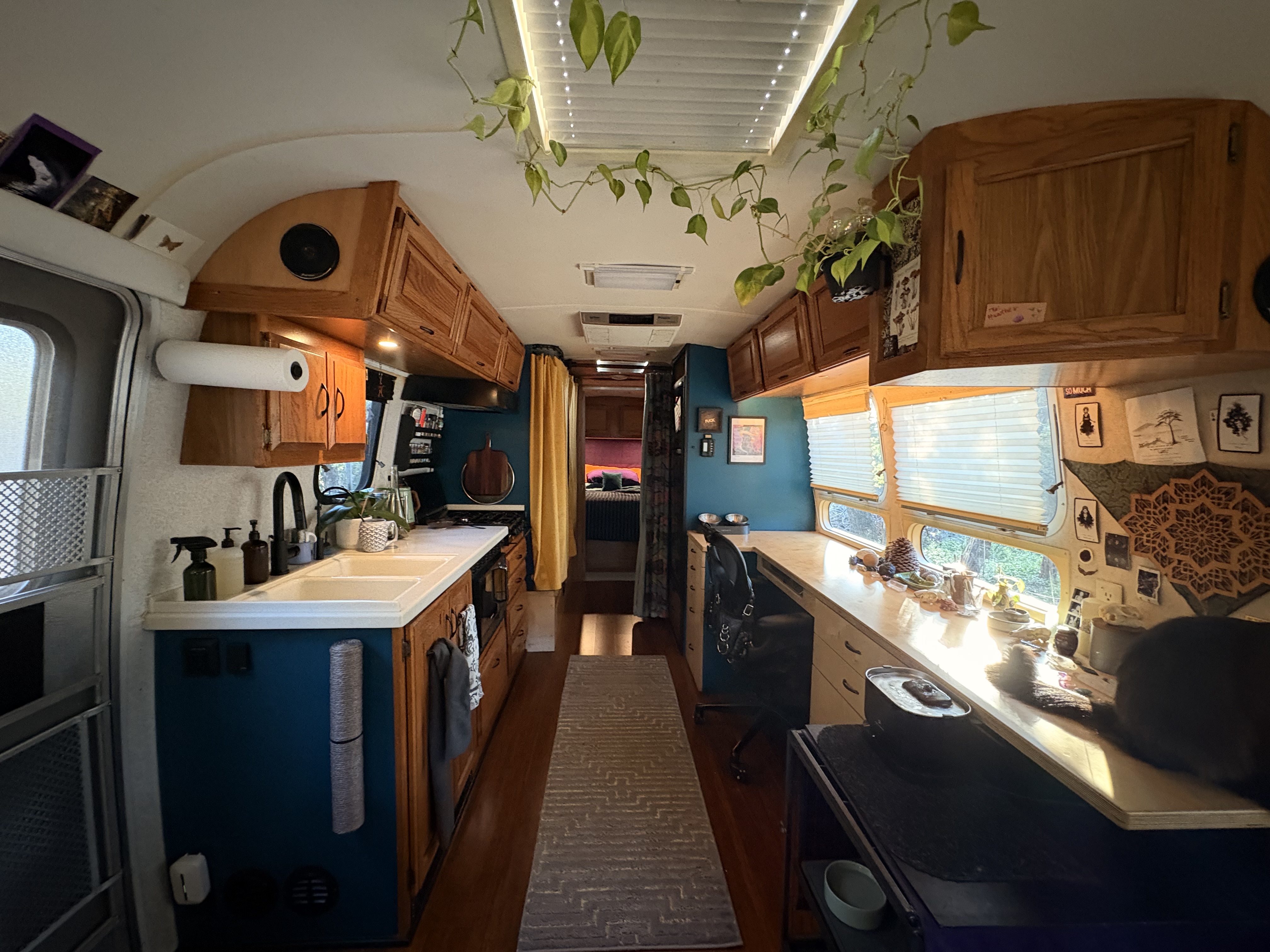 Airstream interior, mid-remodel, teal walls, warm oak cabinets, plants