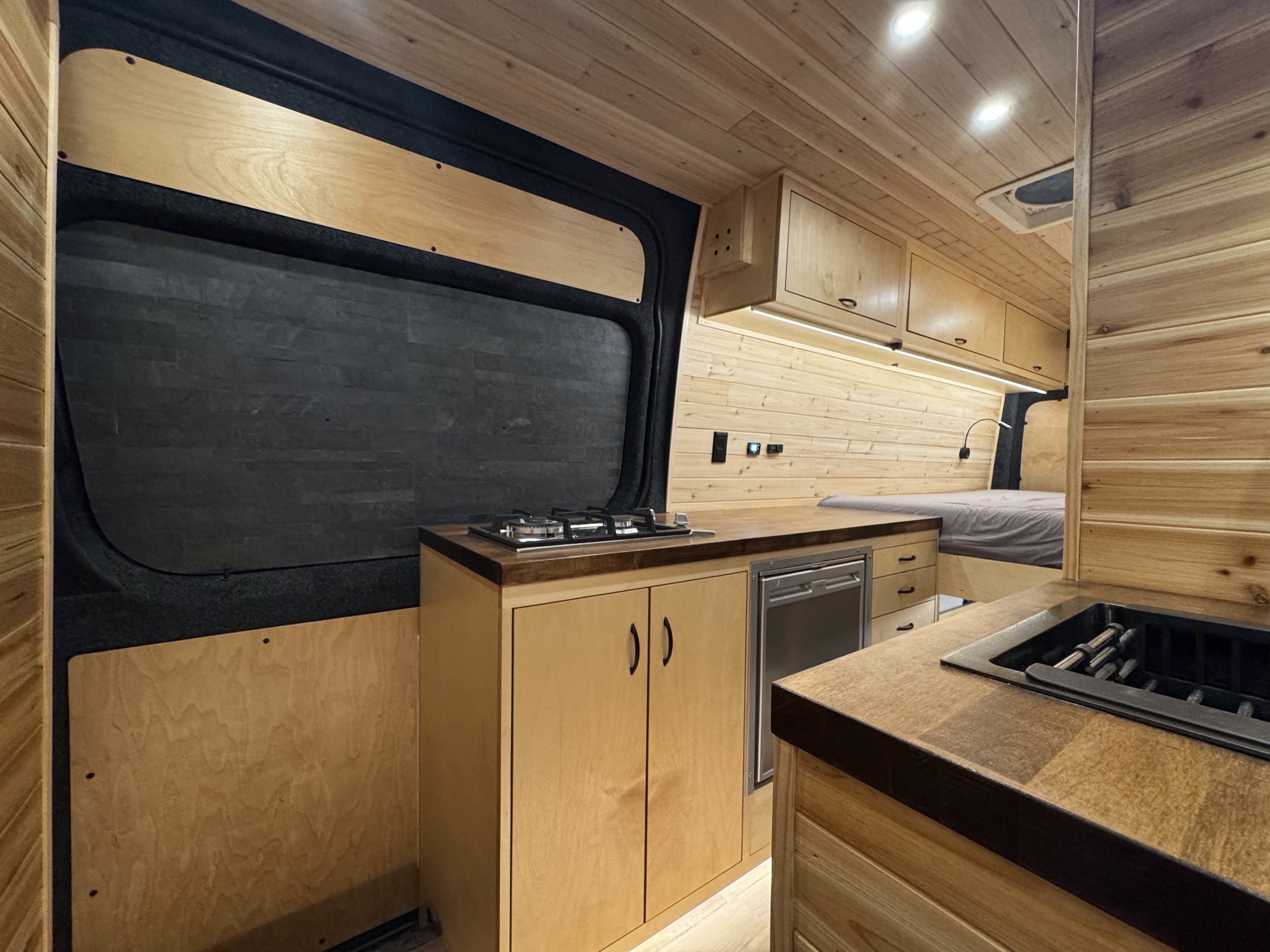 Van bathroom door with hex tile and kitchen beyond